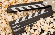 Movie clapperboard laying on top of popcorn - movie themes